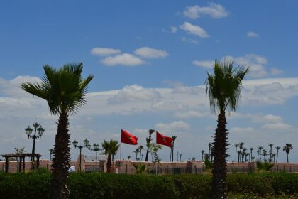 Drapeaux marocains flottant près des remparts de Marrakech sous un ciel bleu