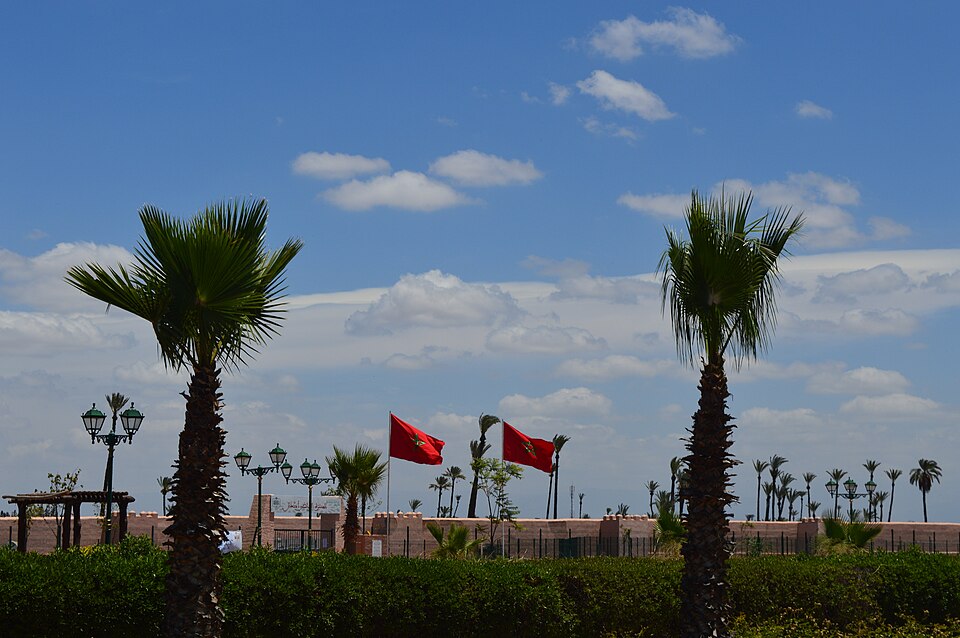 Drapeaux marocains flottant près des remparts de Marrakech sous un ciel bleu