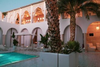 Patio d'un riad à Marrakech au crépuscule, piscine turquoise et palmier — se rafraîchir quand il fait chaud à Marrakech en été.